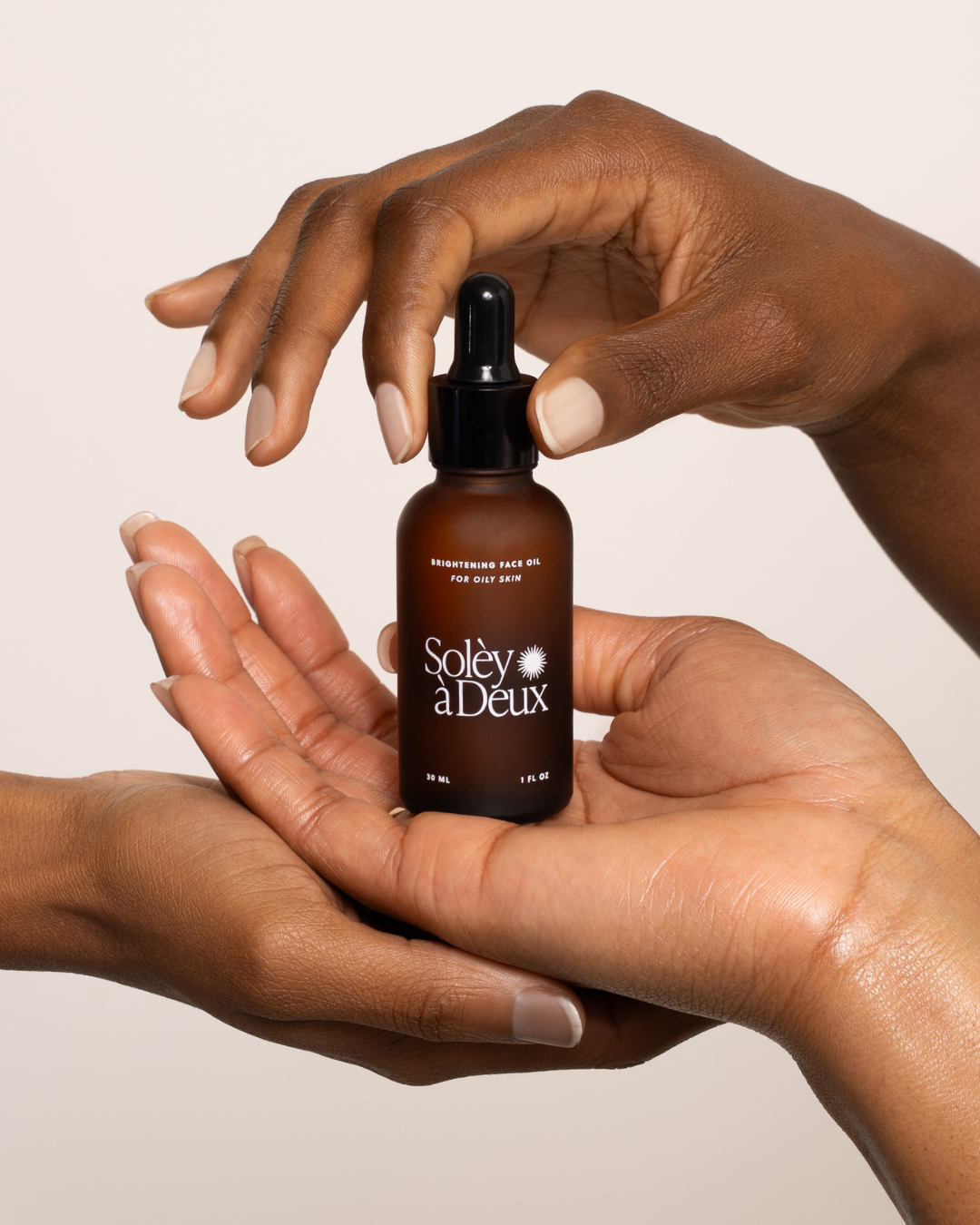 Hands cupping a bottle of Brightening Face Oil for oily skin